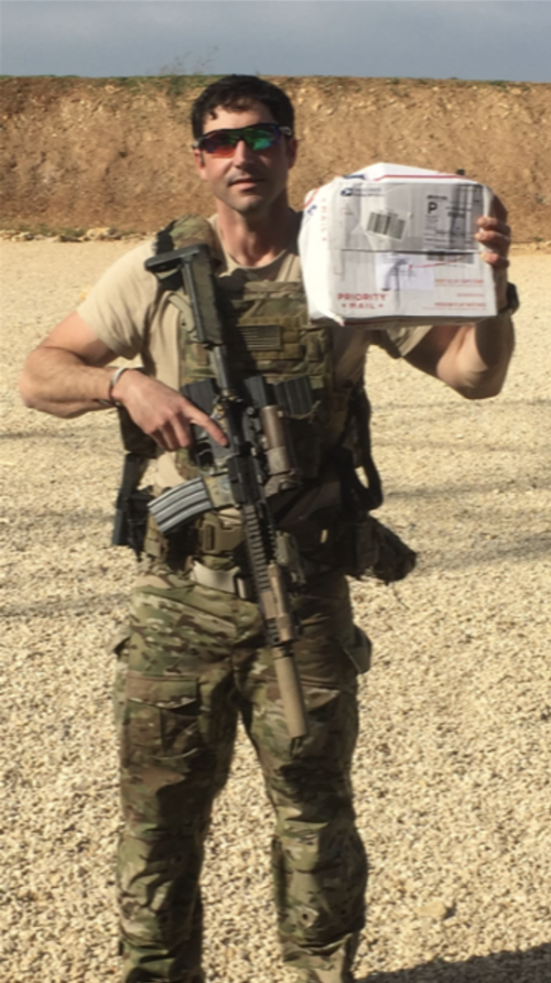Lee on a Special Forces assignment at an undisclosed overseas location, holding a care package sent by UT Austin alumni